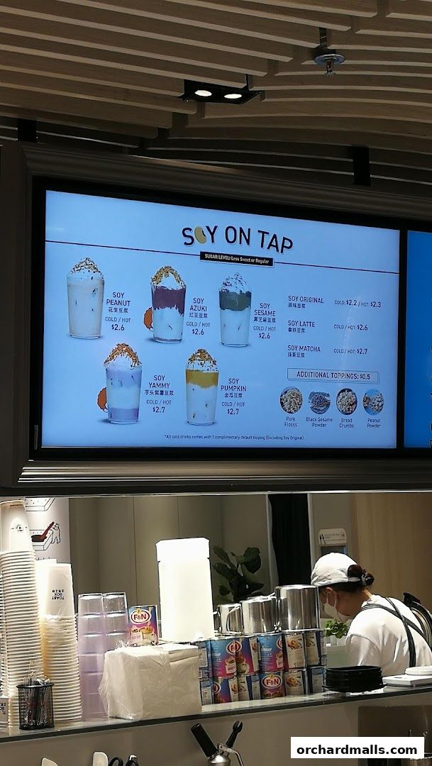 A digital menu board displays various soy drinks with toppings and prices.