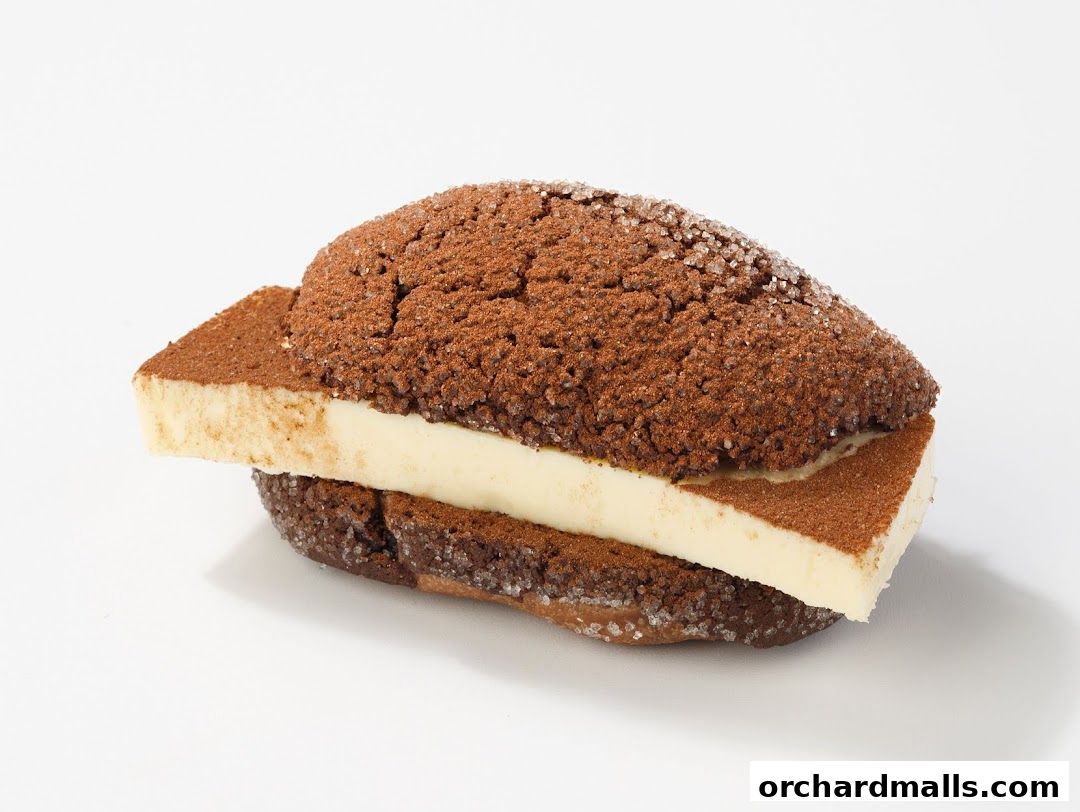 A close-up of a chocolate pastry filled with cream and dusted with cocoa powder.