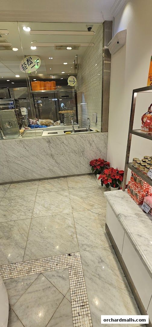 Interior view of a bakery with marble counters, displays, and poinsettia plants.