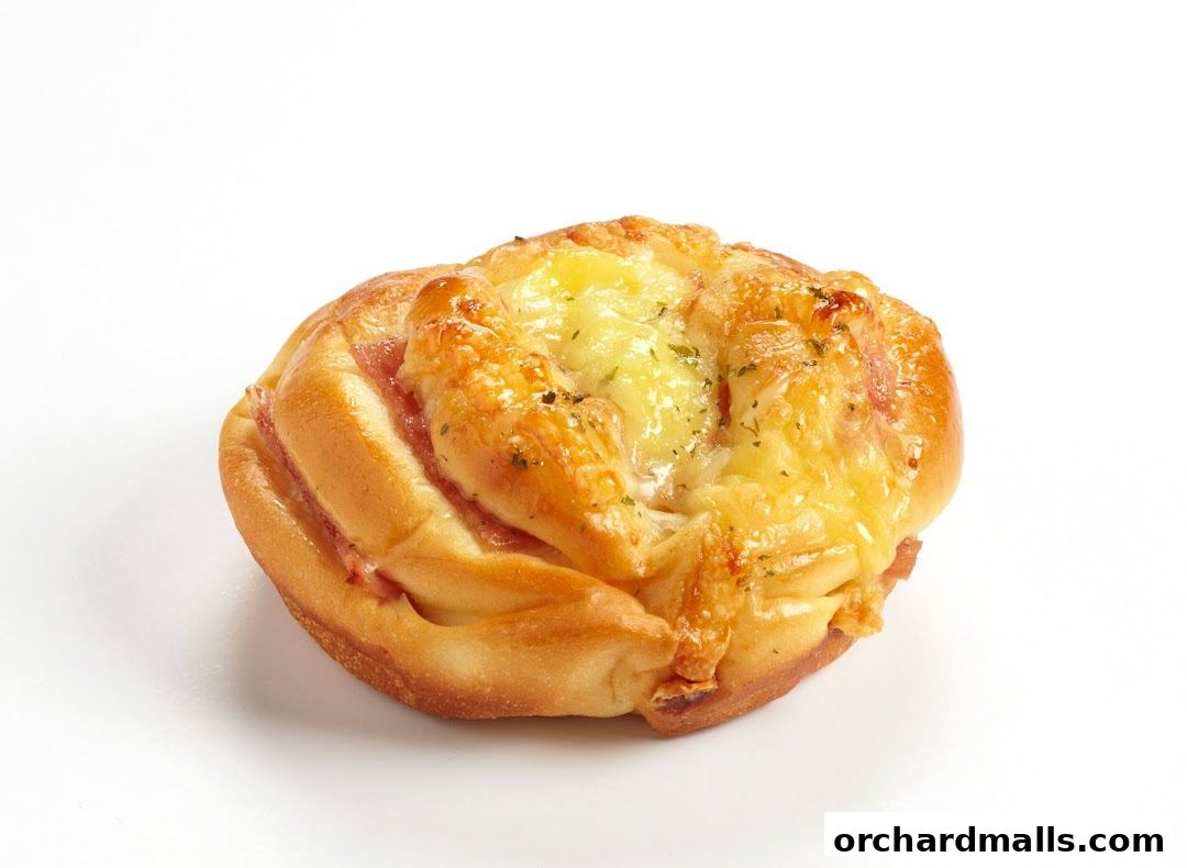 A close-up shot of a savory bread roll with melted cheese and ham.