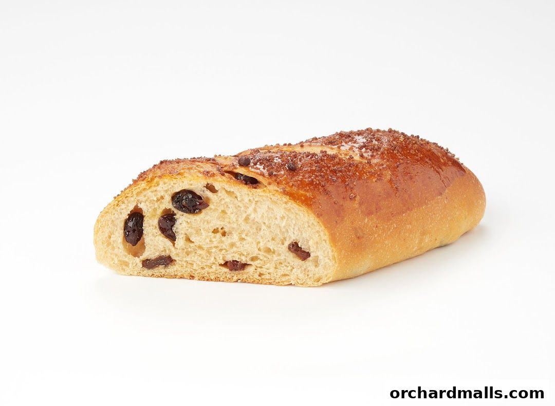 A close-up of a sliced raisin bread loaf with a golden-brown crust.