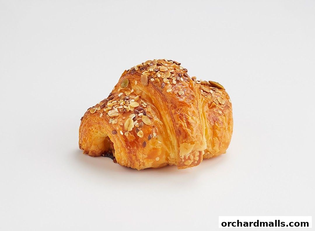 A golden-brown croissant generously topped with a mix of seeds and grains.