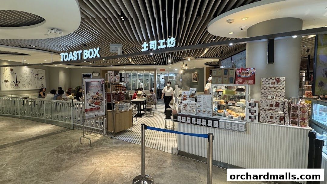 Interior view of a Toast Box cafe with seating, display cases, and staff serving customers.