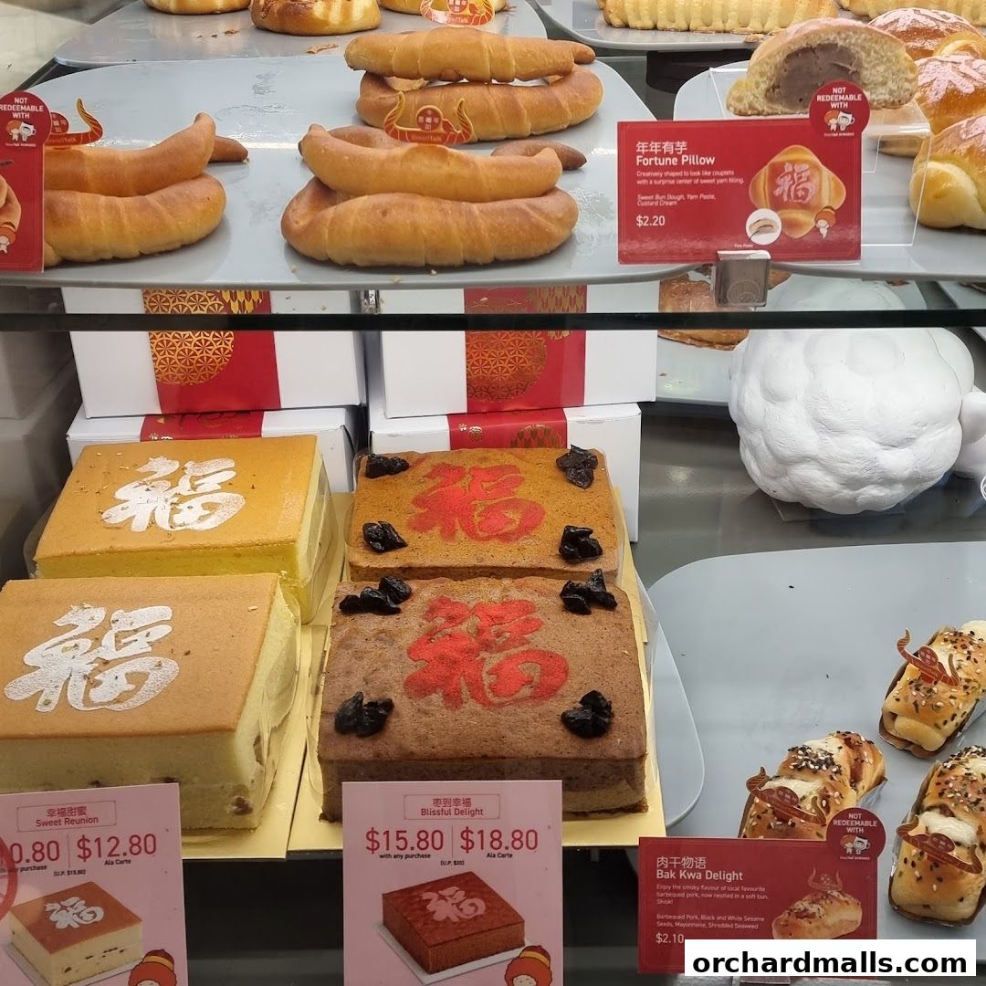 A display of various baked goods, including cakes and buns, with Chinese New Year themed decorations.