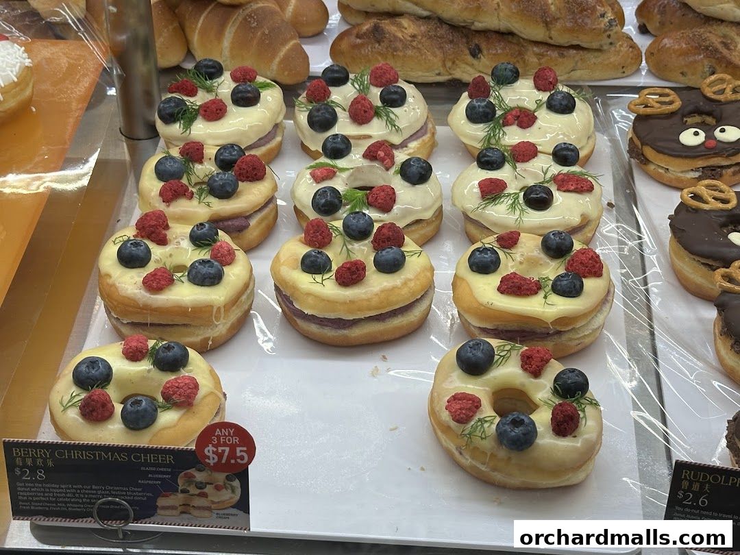 A display of festive donuts topped with berries and cream, alongside other baked goods.