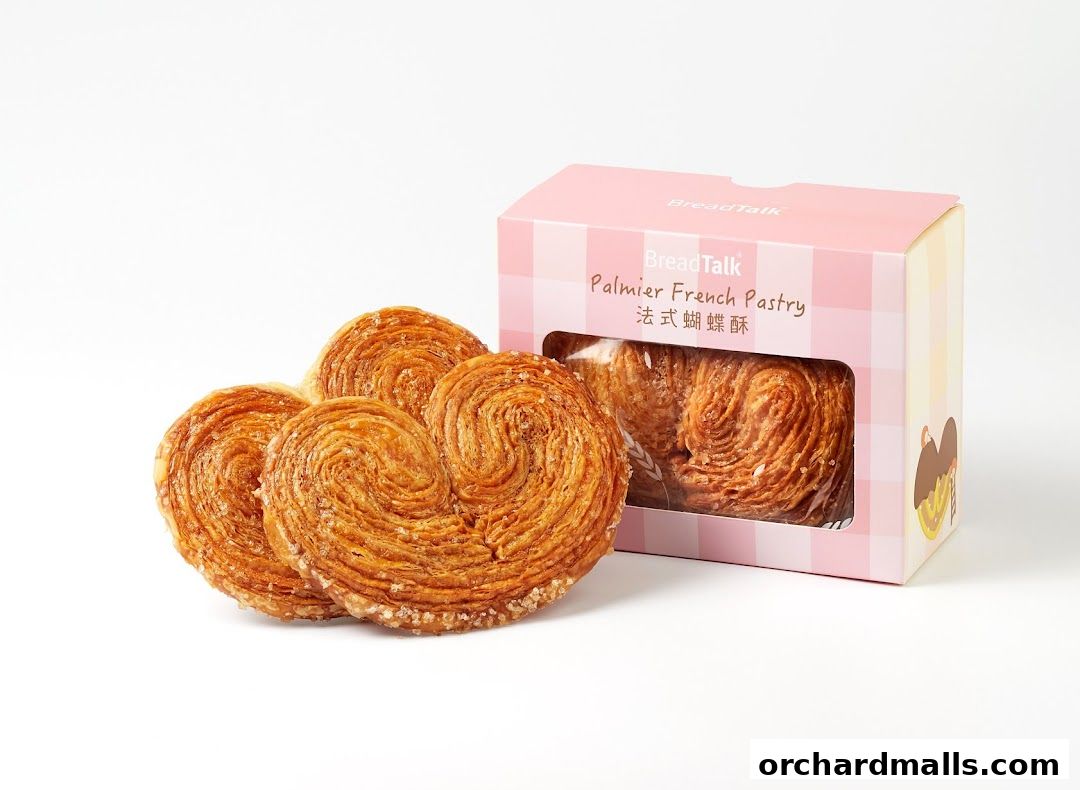 Three golden-brown palmier pastries are displayed next to a pink box from BreadTalk.