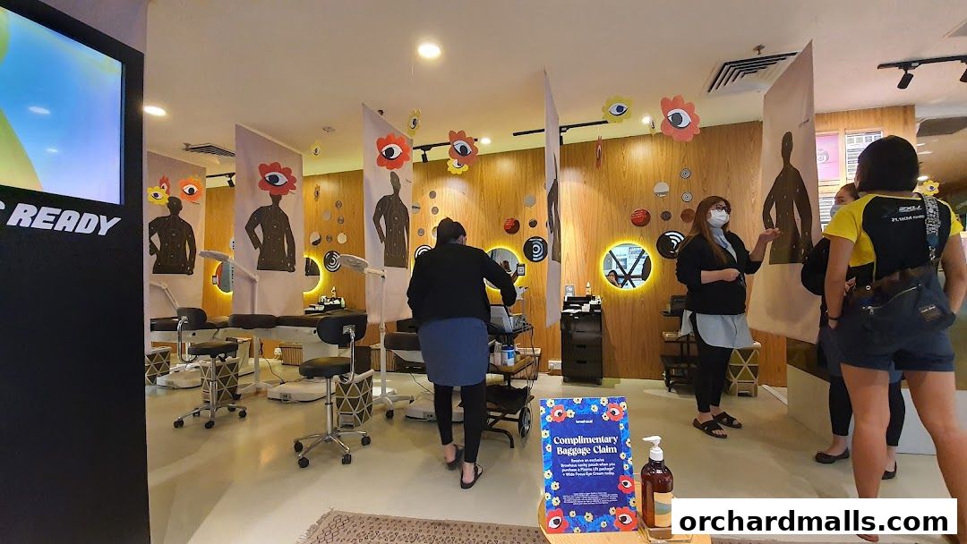 Interior of a beauty salon with treatment beds and staff interacting with customers.