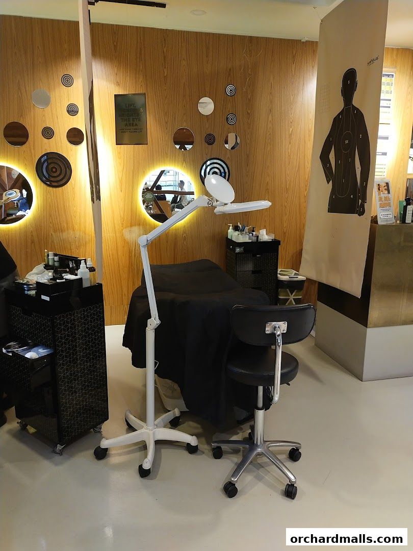 Interior of a beauty salon with a treatment bed, magnifying lamp, and decorative mirrors.