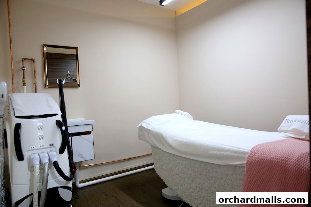 A treatment room with a massage bed, a beauty machine, and a mirror.