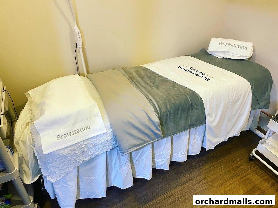 A clean and comfortable beauty treatment bed with branded linens and a lamp.