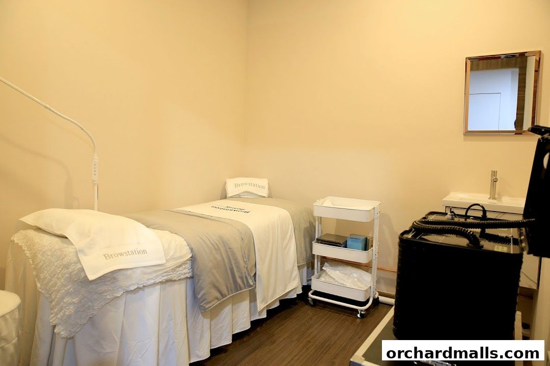 A clean and well-lit treatment room with a massage bed and beauty equipment.