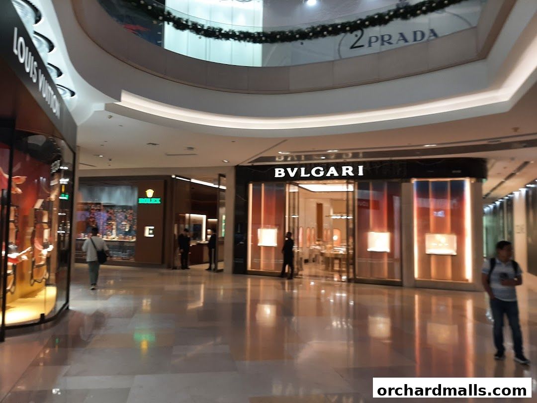 The BVLGARI store entrance is visible in a modern shopping mall, with other luxury brands nearby.
