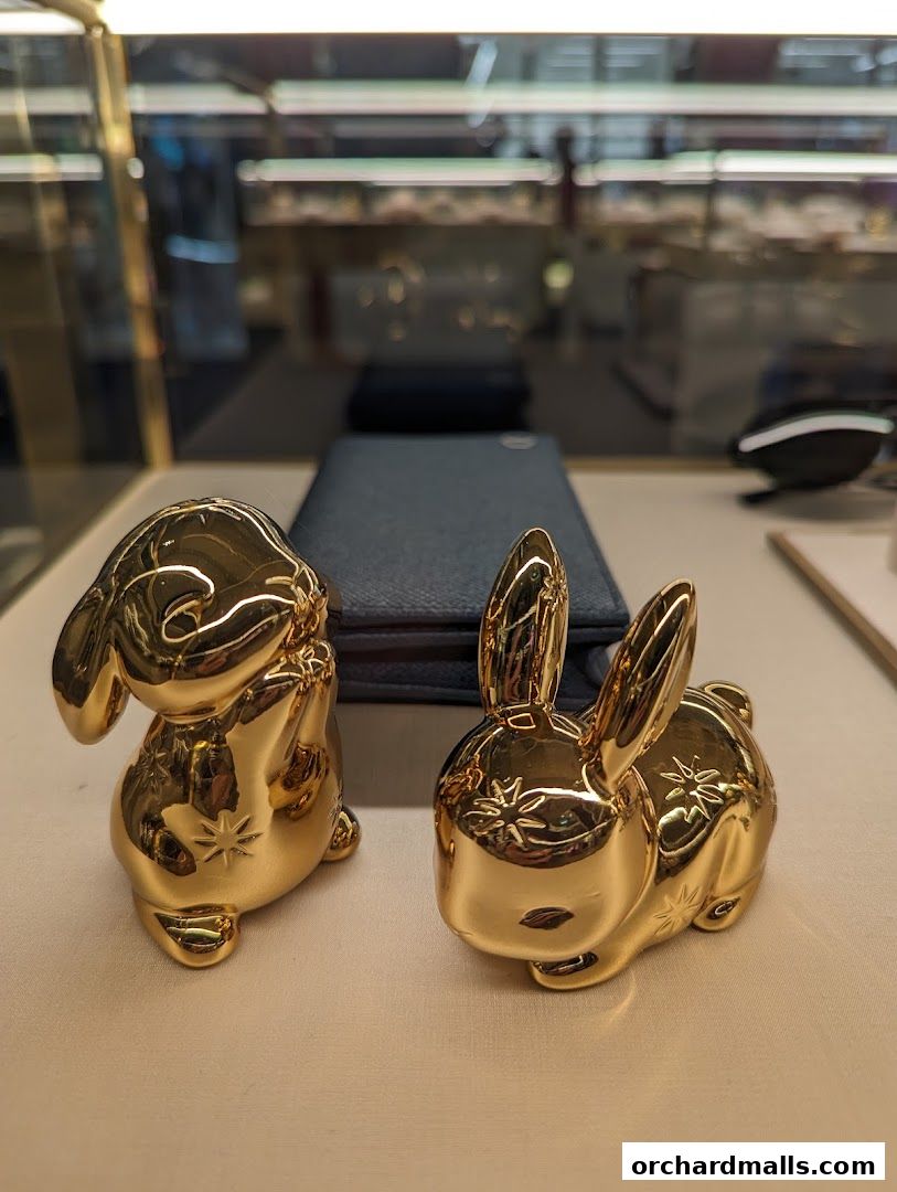 Two shiny golden rabbit figurines displayed in a shop window.