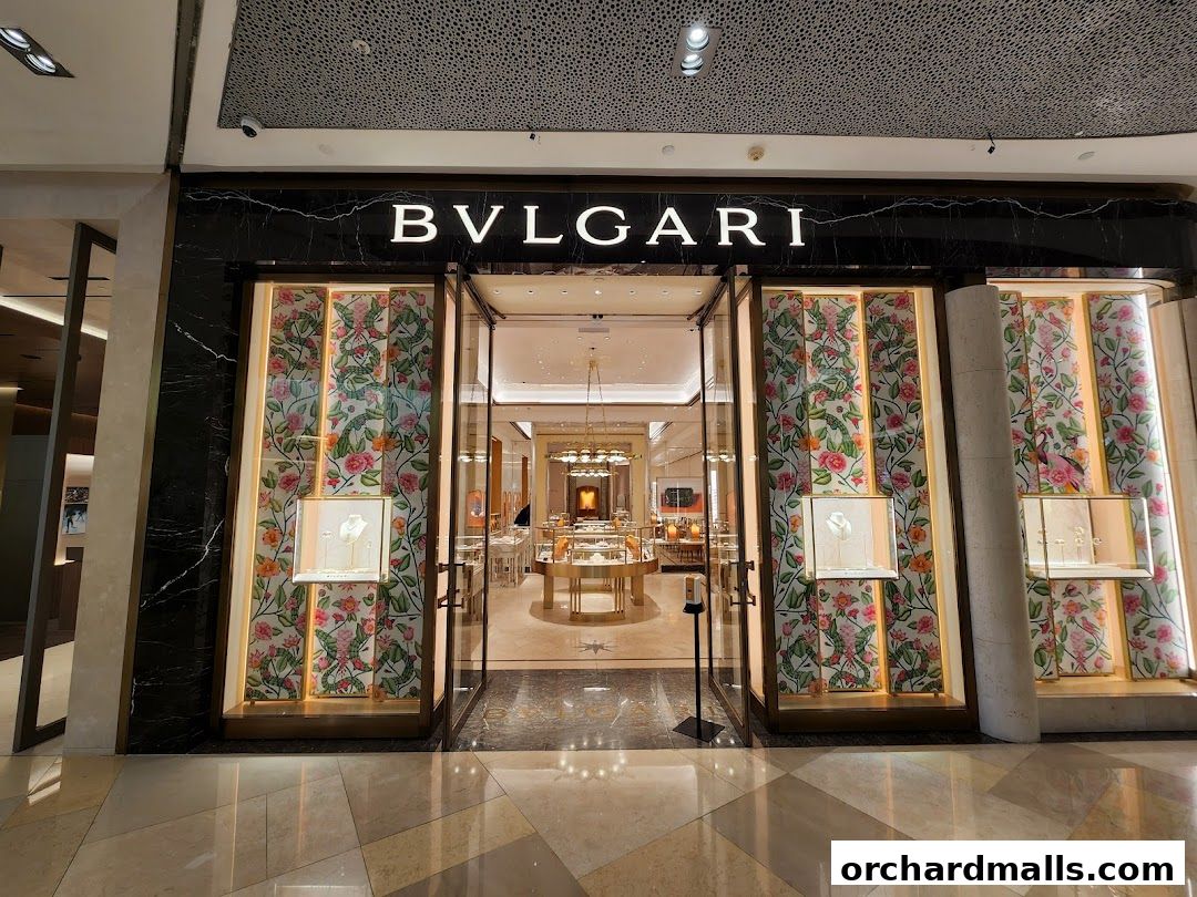 The elegant entrance of a Bulgari store with illuminated displays and floral-patterned windows.