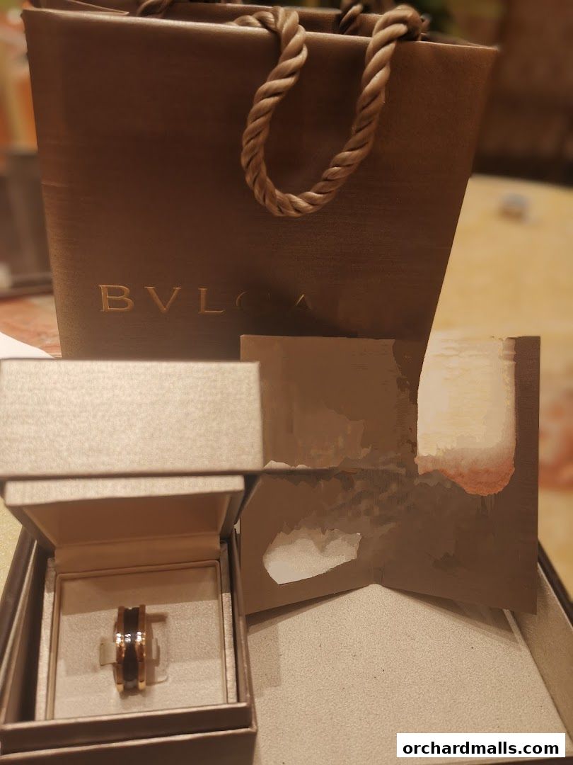 A BVLGARI ring in its box with a shopping bag and card.