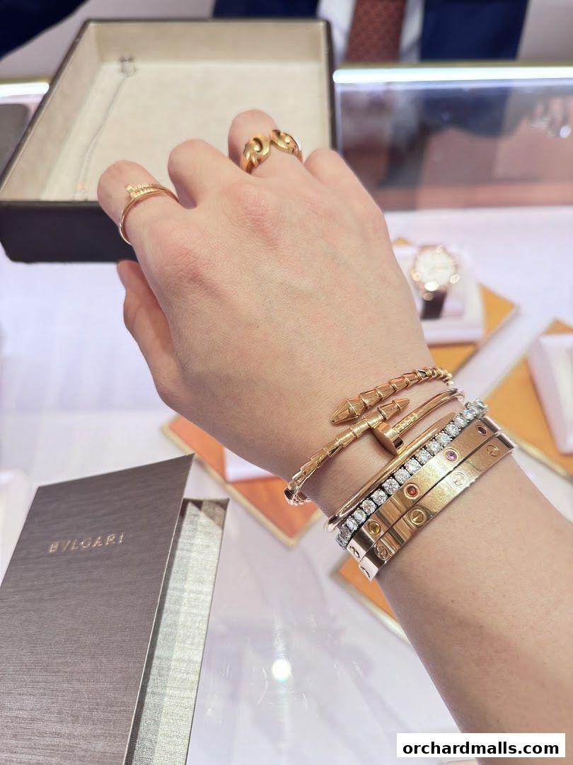 A hand adorned with luxurious Bulgari and Cartier jewelry, showcasing rings and bracelets.