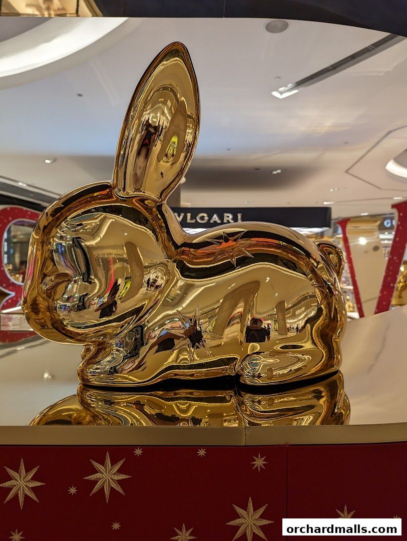 A large, shiny golden rabbit sculpture with a BVLGARI sign in the background.