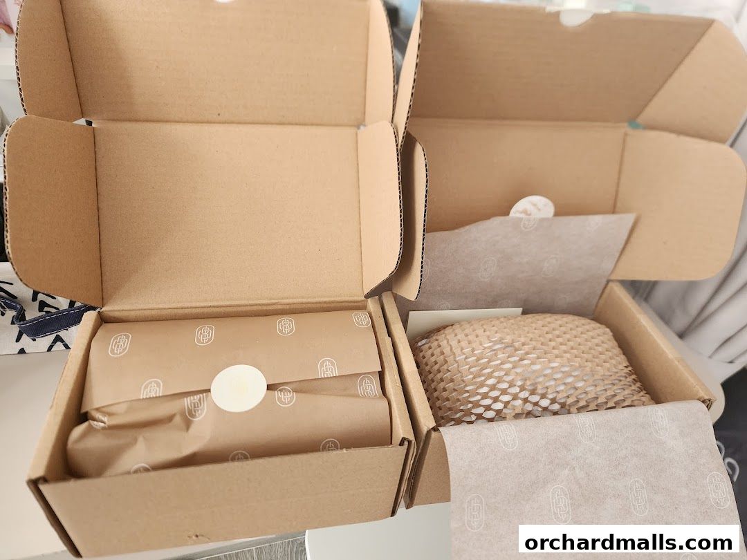 Two open cardboard boxes containing jewelry items wrapped in branded tissue paper.