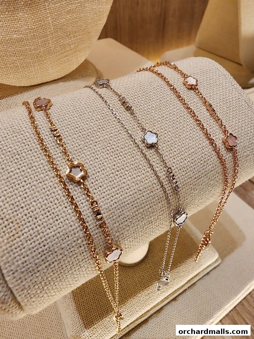 Close-up of delicate rose gold and silver bracelets with clover-shaped mother-of-pearl charms.