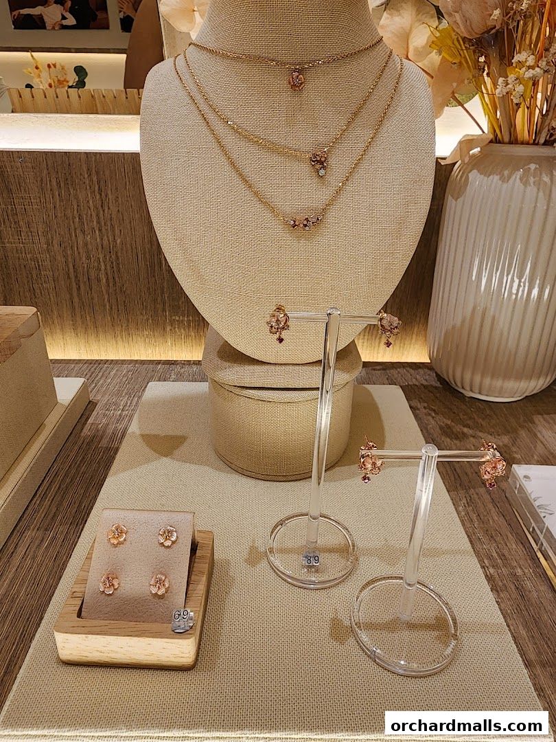 A display of delicate gold necklaces and earrings with floral designs at By Invite Only Jewellery.