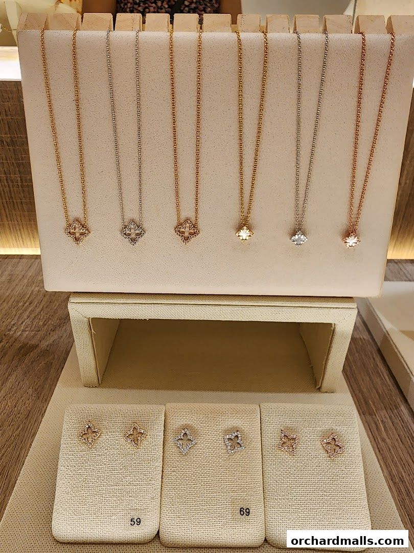 Display of delicate necklaces and earrings with clover-like designs in various metal finishes.