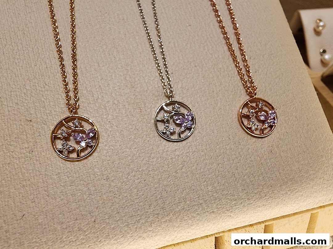 Three delicate necklaces with circular pendants featuring butterfly and floral designs with purple stones.