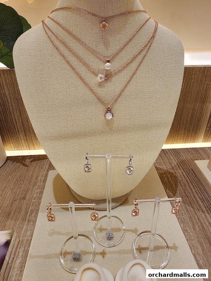 A display of delicate rose gold necklaces and earrings with gemstone and pearl accents.