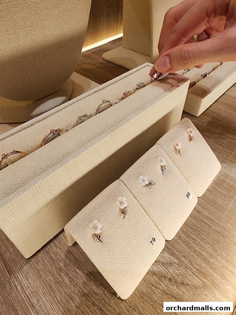 A hand selects a delicate ring from a display of jewelry at By Invite Only Jewellery.