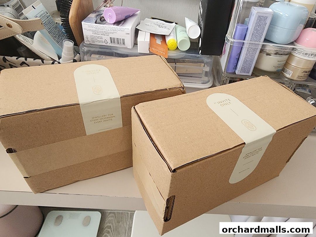 Two cardboard boxes from 'By Invite Only Jewellery' are displayed on a shelf.