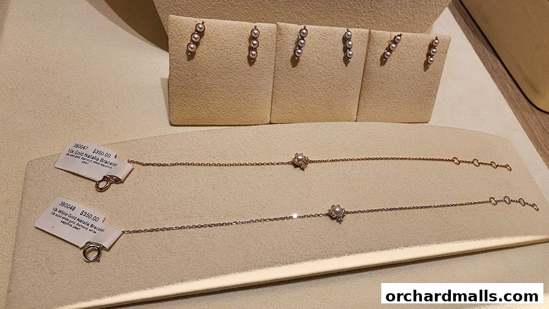 Elegant pearl bracelets displayed on a beige velvet stand at By Invite Only Jewellery.