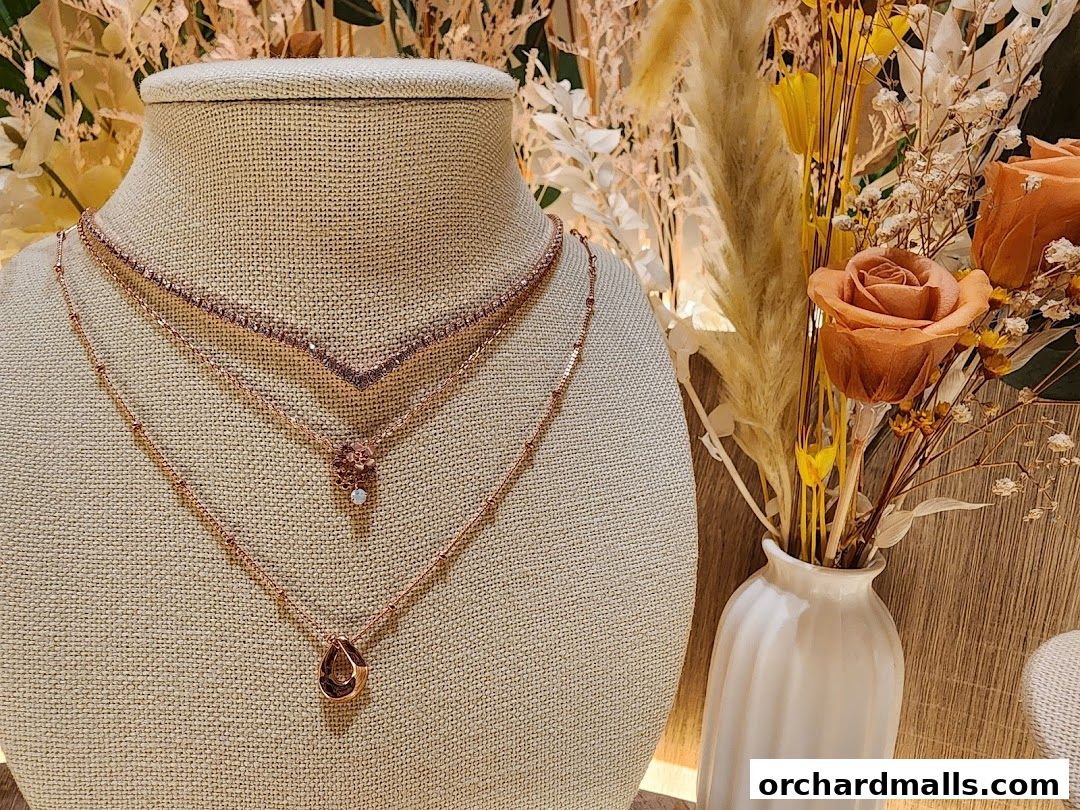 Rose gold necklaces displayed on a mannequin with dried flowers in a vase.
