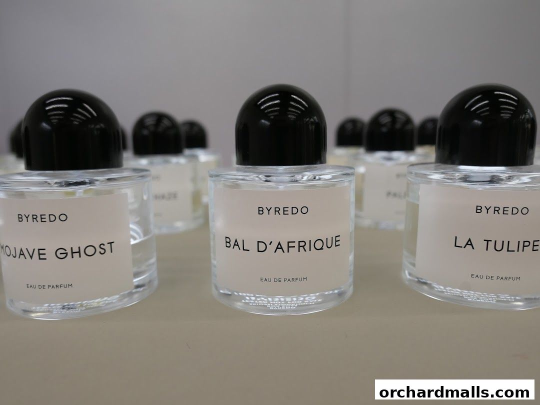 A display of Byredo perfumes, featuring bottles with minimalist labels and black caps.