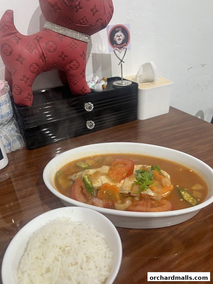 A steaming bowl of fish soup with tomatoes and okra, served with a side of white rice.