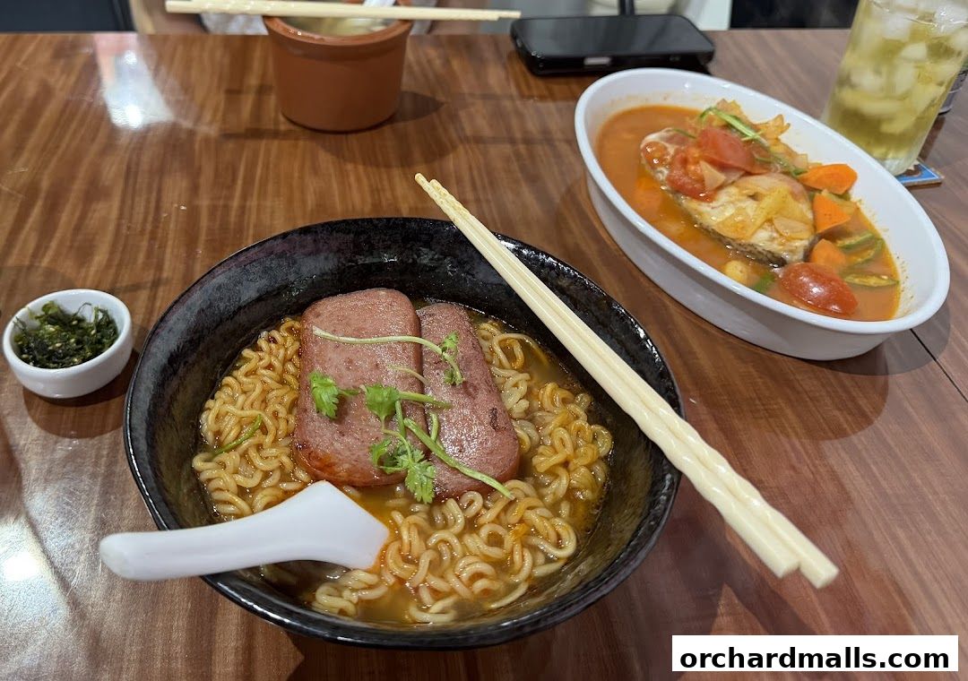 A close-up of a steaming bowl of ramen with spam and a side of seaweed.