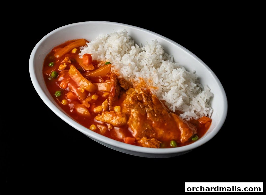 A white bowl filled with rice and a savory chicken dish with vegetables.