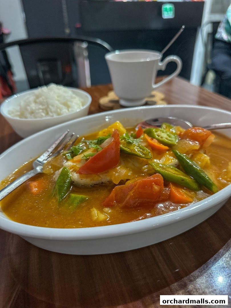 A close-up of a flavorful curry dish with rice and a cup of tea.