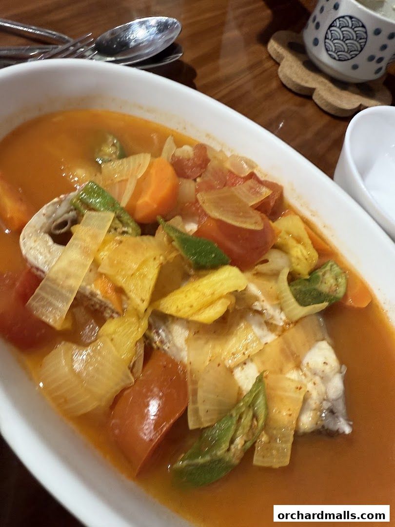 A close-up of a delicious fish stew with vegetables in a white bowl.