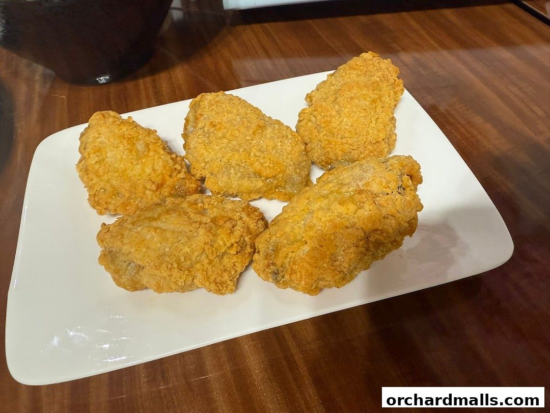 A white plate holds five pieces of golden-brown fried chicken.