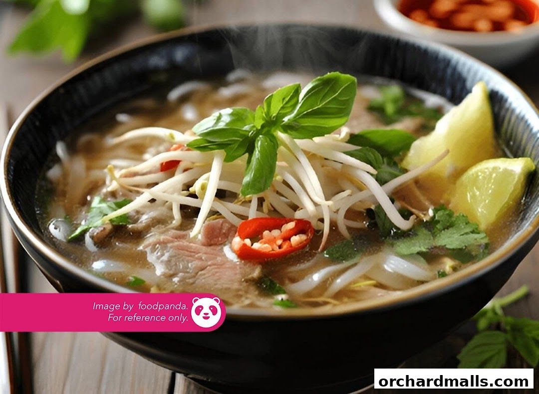 A steaming bowl of pho with beef, bean sprouts, basil, chili, and lime.