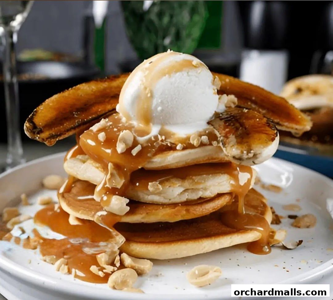 A stack of pancakes topped with ice cream, caramel sauce, and nuts.
