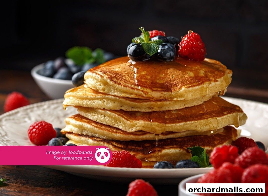 A stack of fluffy pancakes topped with berries and syrup, served on a plate.
