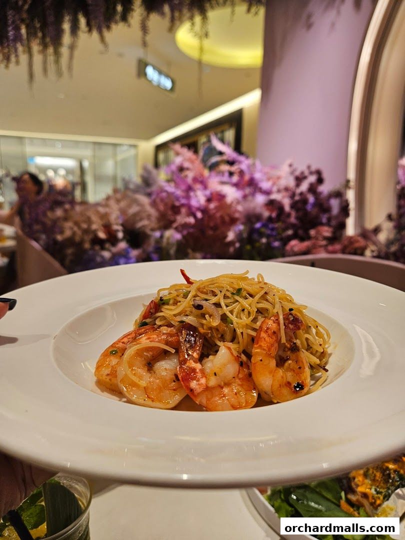 A plate of shrimp pasta served in a stylish restaurant with floral decor.