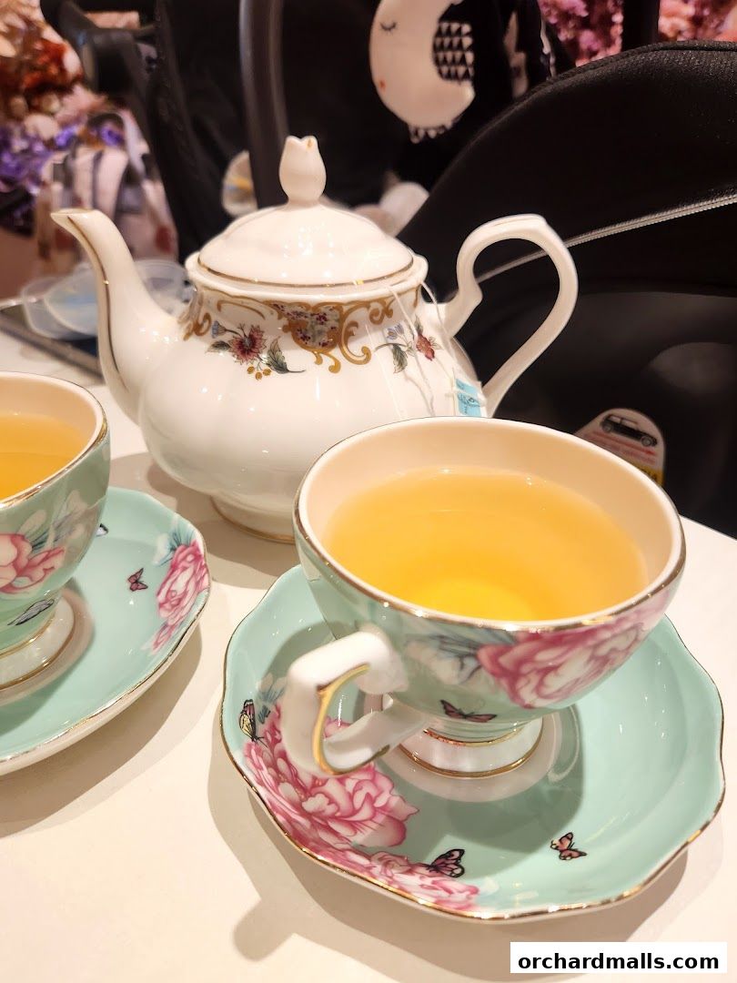 A beautifully decorated teapot and teacups filled with golden tea.