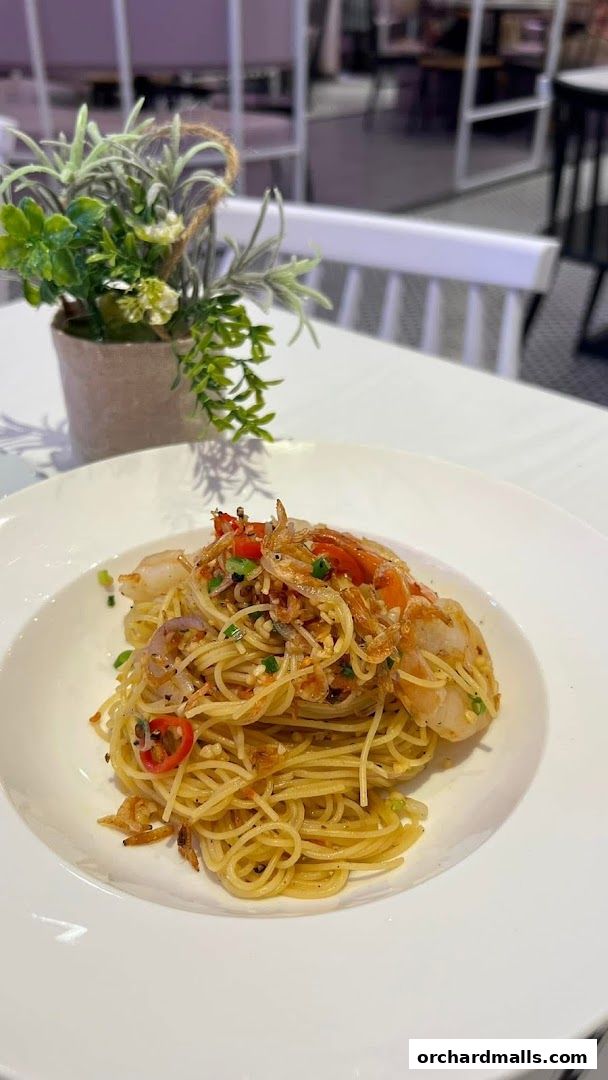 A plate of spaghetti with shrimp and chili, garnished with herbs and crispy bits.