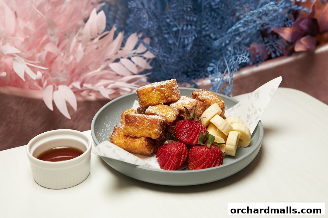 A plate of French toast bites with strawberries, bananas, and a side of syrup.