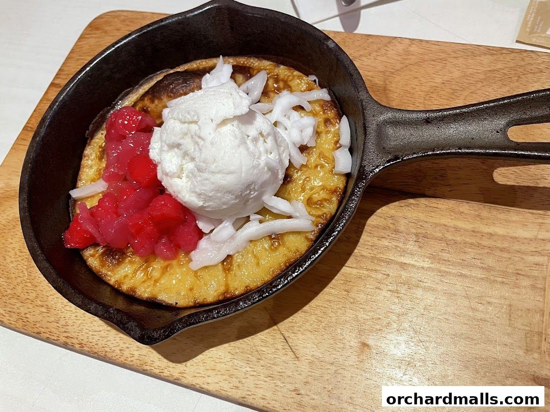 A warm dessert served in a cast-iron skillet with ice cream and toppings.