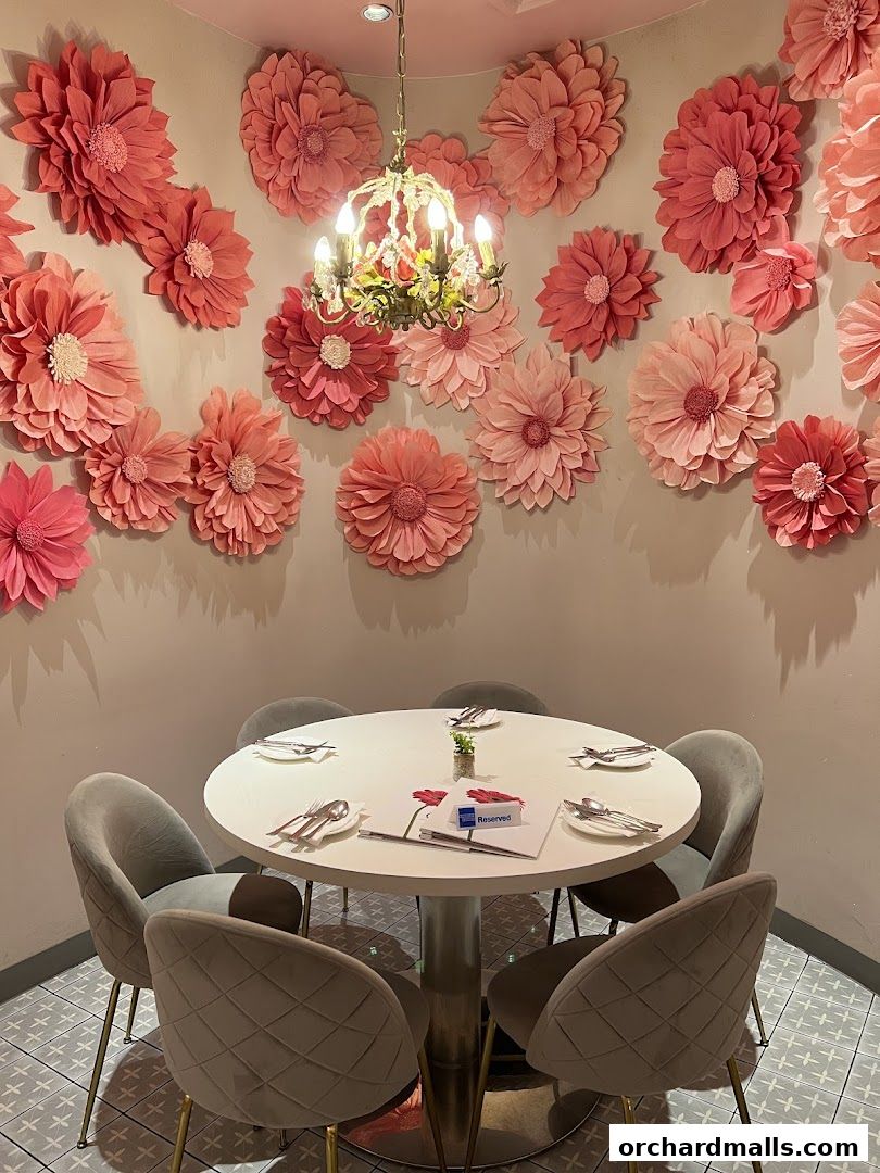 A round table set for dining, adorned with floral decorations and a chandelier.