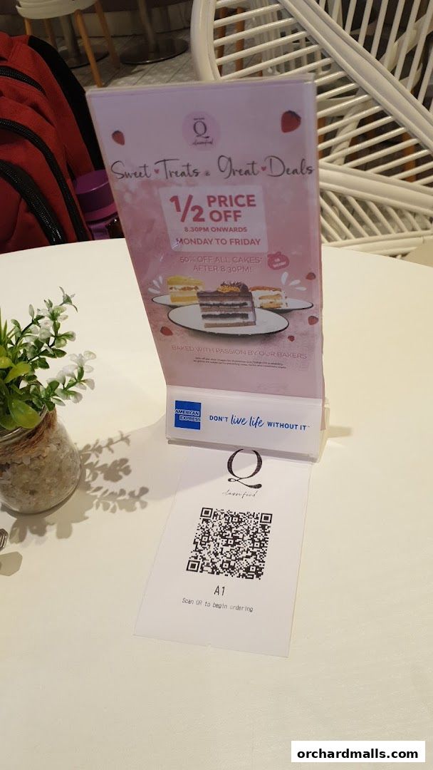 A table tent menu for Cafe Q Classified advertising a half-price cake deal.
