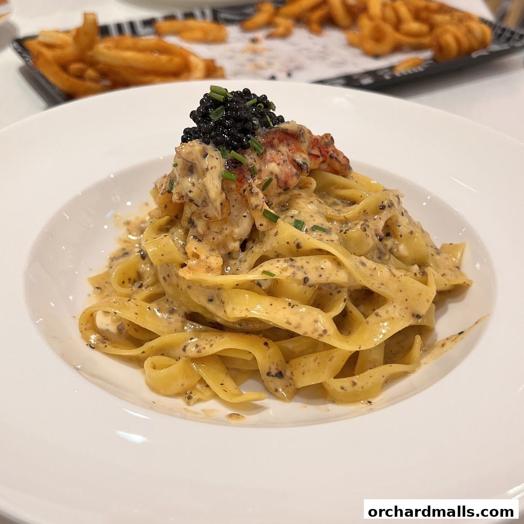 A close-up of a decadent pasta dish topped with lobster and caviar.