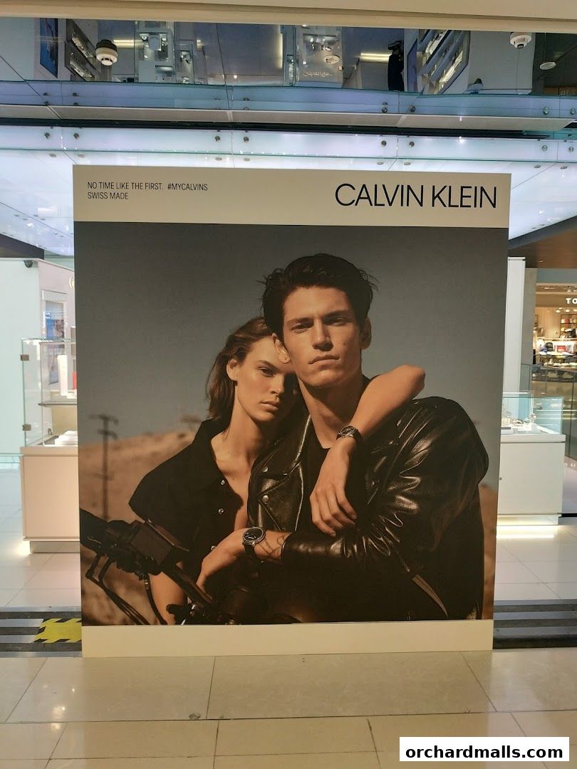 Calvin Klein advertisement featuring a couple wearing watches and leather jackets.